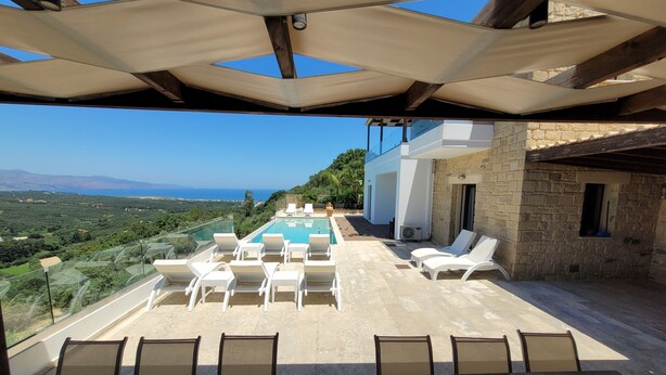 Zona de piscina en la azotea con sillones y vista al mar.