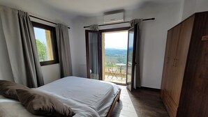 Un dormitorio con cama, armario y balcón con mesa y sillas.