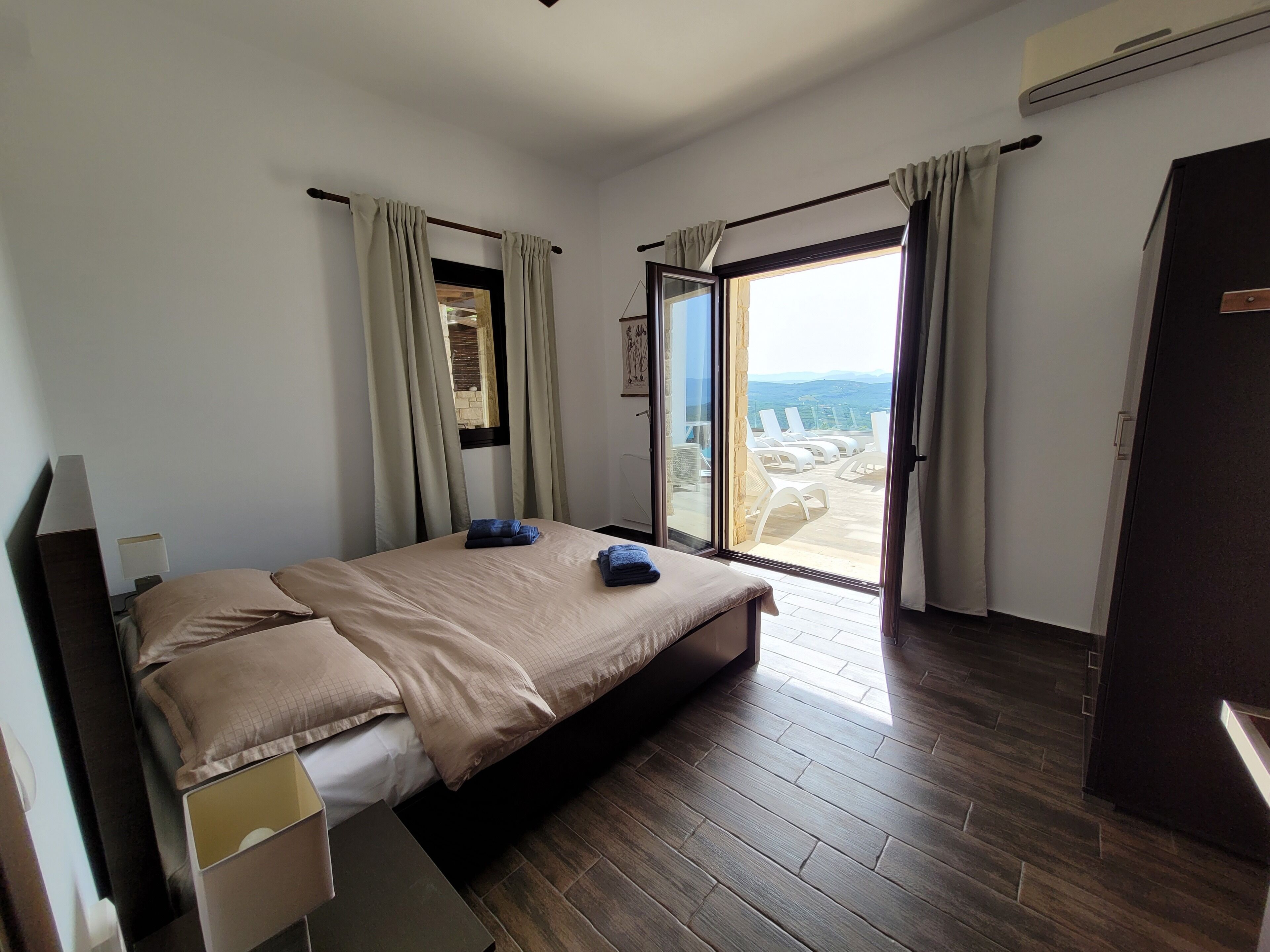 Habitación de hotel moderna con una cama grande, puerta corrediza de vidrio a un balcón y vista al paisaje.