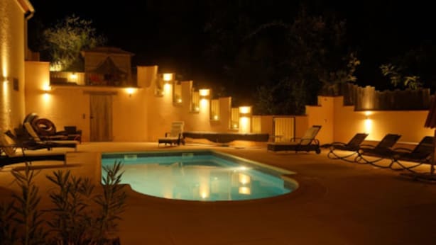 A swimming pool with lounge chairs and a building with warm lighting. - Large fully air conditioned luxury villa with pool in beautiful location (Reynès)