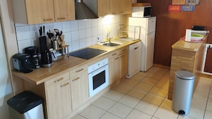 A compact kitchen with wooden cabinets, a microwave, a dishwasher, and a stainless steel trash bin. - Appt T4, 8 pers, 84m2 in chalet in calm close tracks, Ax 3 Domaines Bonascre (Ax-Les-Thermes)