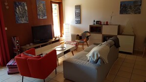 A living room with a TV, sofa, red chair, and a small table. - Appt T4, 8 pers, 84m2 in chalet in calm close tracks, Ax 3 Domaines Bonascre (Ax-Les-Thermes)