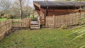 Una cabana de fusta amb terrassa i tanca de fusta.