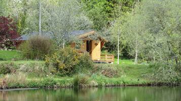 Escape to a serene cabin surrounded by lush greenery and a tranquil pond.
