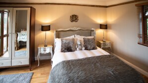 Une chambre à coucher avec un grand lit, deux tables de chevet, un miroir et une fenêtre avec des stores.