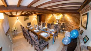 Une salle à manger avec un mur en briques, des poutres en bois et une table dressée pour six personnes.