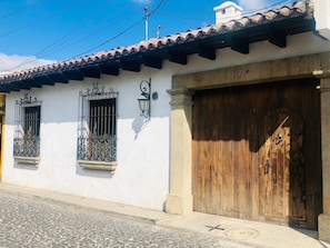 A building with a tiled roof, two windows with wrought iron grilles, and a wooden door. - Hotel La Casa de Don Moncho (Antigua Guatemala)