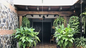A courtyard with a stone wall, wooden beams, and potted plants. - Hotel La Casa de Don Moncho (Antigua Guatemala)