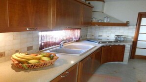 Una cocina con gabinetes de madera, un lavamanos doble y una cesta de frutas en la encimera.