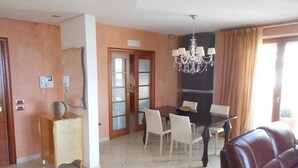 Un comedor con una araña, una mesa de comedor con sillas y un sofá de cuero.