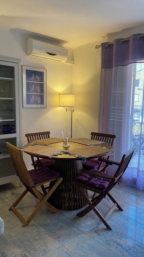 A round dining table with chairs, a floor lamp, and a wall-mounted air conditioner.