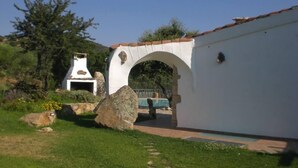 Edifici blanc amb arc de pedra, una llar de foc de pedra i zona de piscina.