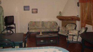 Un saló tranquil amb un sofà, cadires, una taula de centre i una televisió.