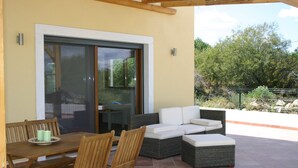 Une terrasse extérieure avec une table à manger, des chaises et un canapé.