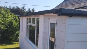 A white mobile home with two windows and a dark roof. - 3 bedroom holiday bungalow on the beach front, Point Clear Essex (Clacton)