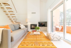 Ein modernes Wohnzimmer mit einer Couch, einem Couchtisch, einem Fernseher und einer Treppe.