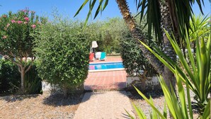 A pathway leading to a pool area surrounded by greenery and a clear blue sky. - Spacious Seville Cortijo with large private pool set in orange groves free wifi (Lora Del Rio)