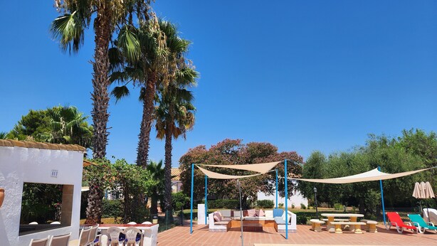 A pool area with lounge chairs, a small pool, and palm trees. - Spacious Seville Cortijo with large private pool set in orange groves free wifi (Lora Del Rio)