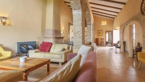 A spacious living area with a high ceiling, stone columns, and a fireplace. - Spacious Seville Cortijo with large private pool set in orange groves free wifi (Lora Del Rio)