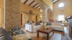 A spacious living room with a fireplace, white sofas, and a coffee table. - Spacious Seville Cortijo with large private pool set in orange groves free wifi (Lora Del Rio)