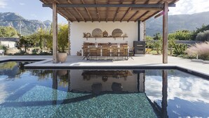 A pool area with a pergola, a bar setup, and a view of mountains.
