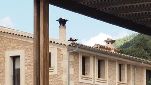 A stone building with a tiled roof, a chimney, and a covered patio area.