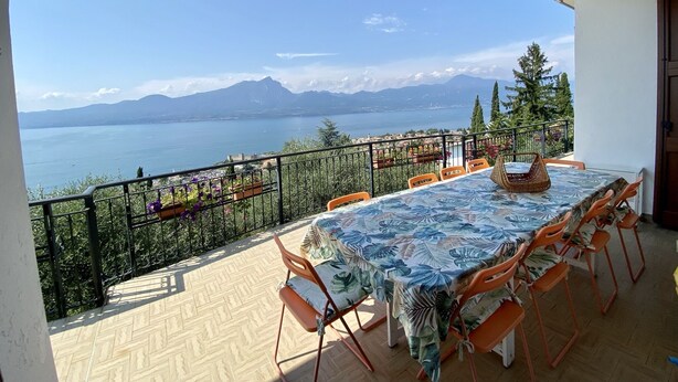 A terrace with a table and chairs, overlooking a lake and mountains. - Villa I Gelsomini,  6 Bedrooms, Garden, Terrace, Stunning View of Lake Garda (TORRI DEL BENACO - VENETO)