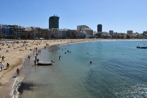 A beach with a boat docked near the shore, surrounded by buildings and clear blue water. - APARTMENT WITH FANTASTIC VIEWS (Balcon de Telde)