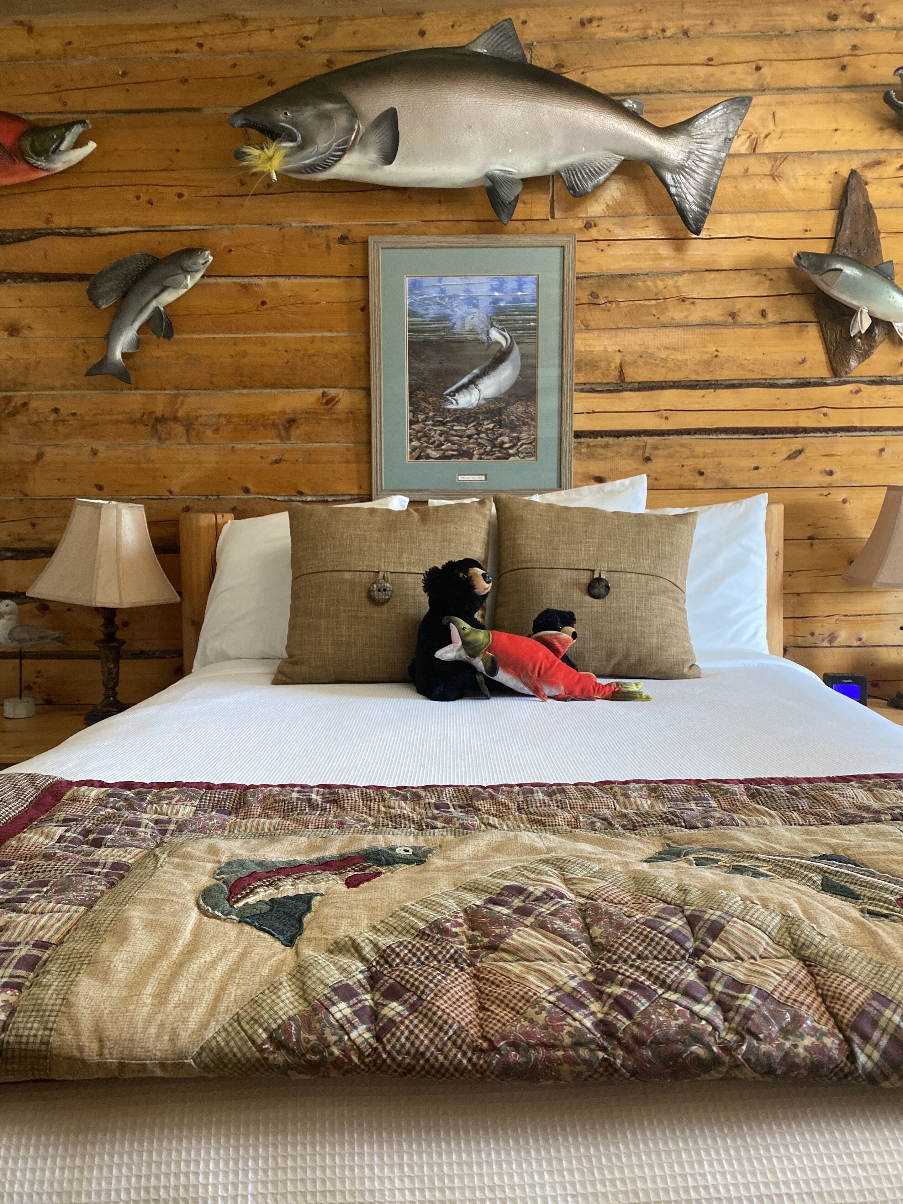 A bedroom with a bed, pillows, a quilt, and fish-themed decorations on the wall.