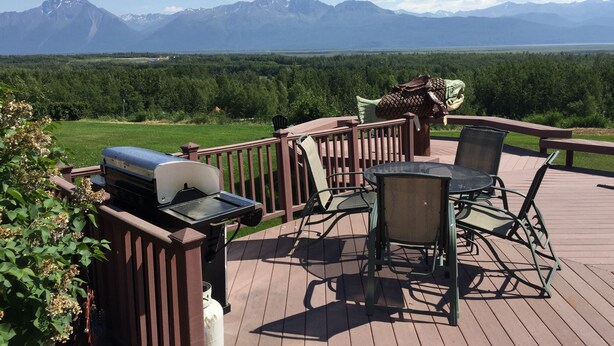 A deck with outdoor furniture, a grill, and a view of mountains. - Pioneer Ridge B&B Inn (Wasilla)