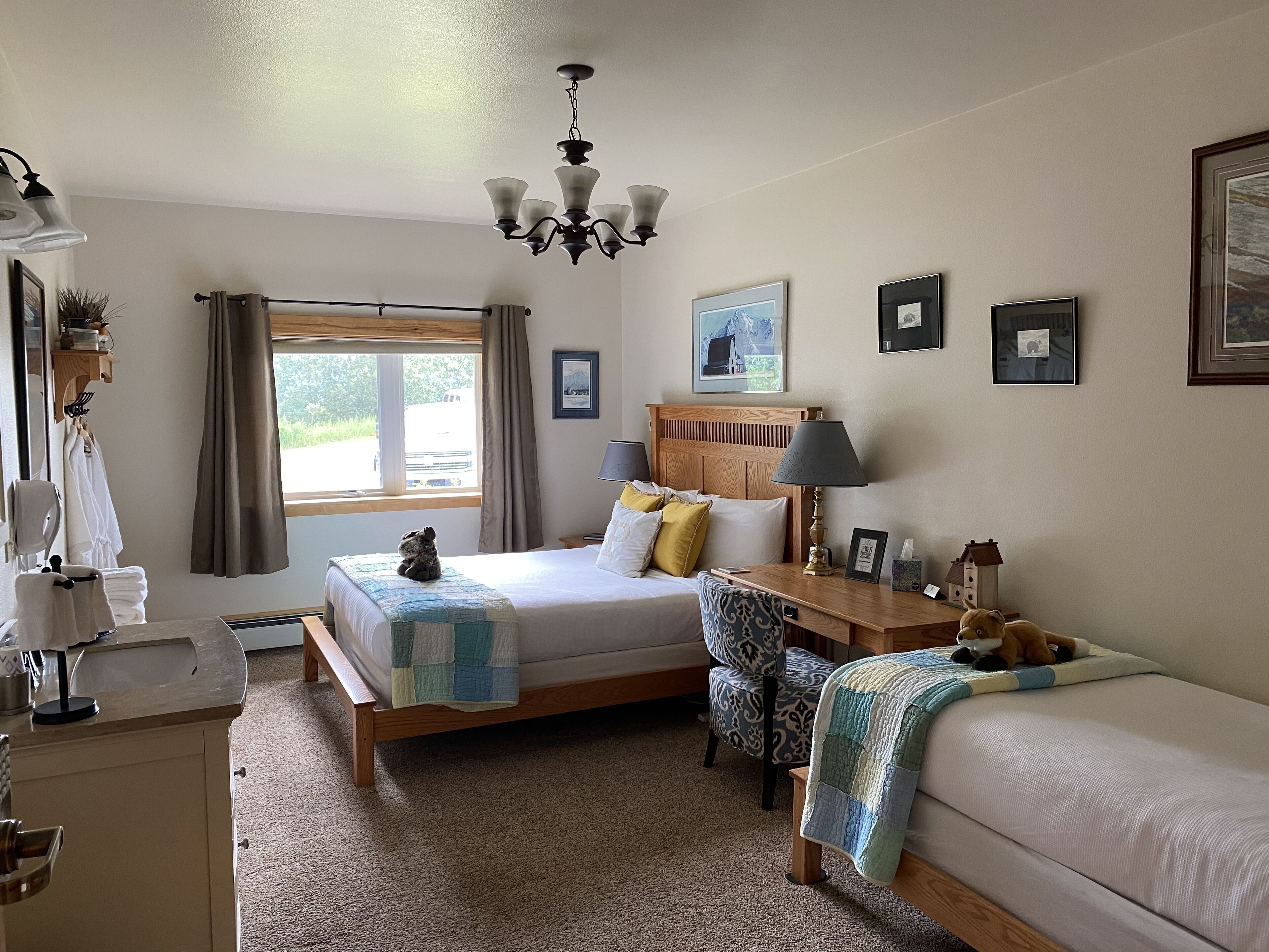 A well-lit bedroom with a large bed, bedside tables, a chair, and a window with curtains.