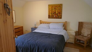 A bedroom with a bed, wooden nightstands, a chair, a wall art piece, and a door.