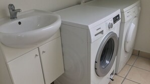 A compact laundry area with a sink and a front-loading washing machine. - Holiday home with beautiful sea views. (Frørup)