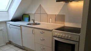 A compact kitchen with a built-in oven, a sink, and a window above the countertop. - Holiday home with beautiful sea views. (Frørup)