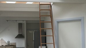 A kitchen with a skylight, a wooden ladder, a refrigerator, and a stove. - Holiday home with beautiful sea views. (Frørup)
