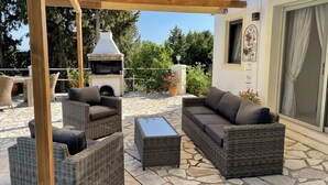An outdoor patio with wicker furniture, a stone floor, and a wood pergola.