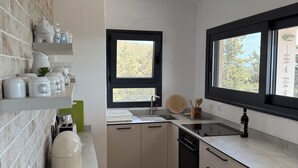 A modern kitchen with white cabinets, a black countertop, a window, and a green bowl.