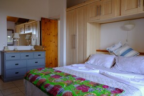 A bedroom with a bed, a dresser, a mirror, and wooden cabinets.