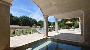 Ein Außenpoolbereich mit Pergola, Liegestühlen und Blick auf die umliegende Landschaft.