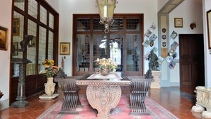 Ein traditionell eingerichteter Raum mit Holzbalkendecke, einem großen Fenster mit Aussicht, einem Tisch mit Blumenvase und Wanddekorationen.