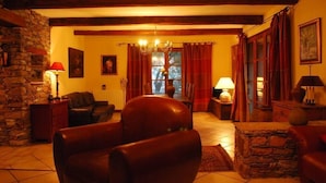 A cozy living room with a stone wall, leather sofa, wooden beams, and a chandelier. - Bastia charming building - Corsica 3 minutes from the beaches (Bastia)