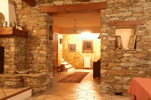 A stone-walled hallway leading to a dining area with a red tablecloth.