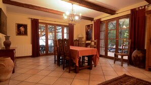 A dining area with a table set for four, wooden chairs, a chandelier, and large windows with curtains. - Bastia charming building - Corsica 3 minutes from the beaches (Bastia)