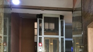 Ein Eingangsbereich mit Marmorboden, einem Metallgitter und einer Treppe, die nach oben führt.