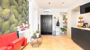 Ein modernes Wohnzimmer mit einem roten Sofa, einem kleinen runden Tisch mit einer Pflanze und einer schwarzen Tür im Hintergrund.