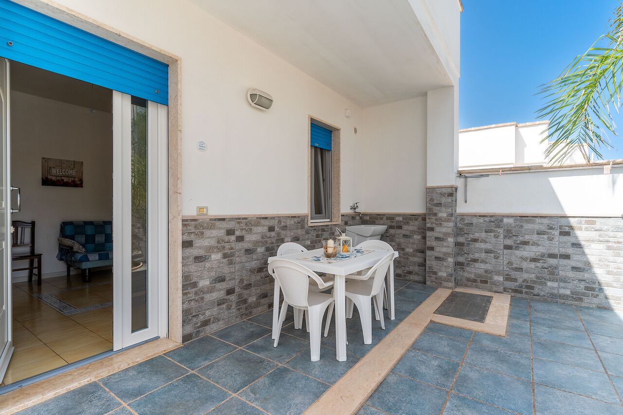 A patio area with a table and chairs, a sliding glass door, and a blue awning.