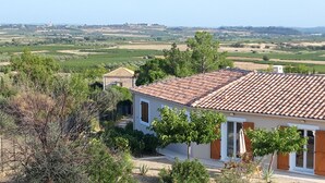 Une maison avec un toit en tuiles, entourée de verdure et de champs.