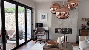 Un salon moderne avec une table basse en verre, un pouf rond et une cheminée.