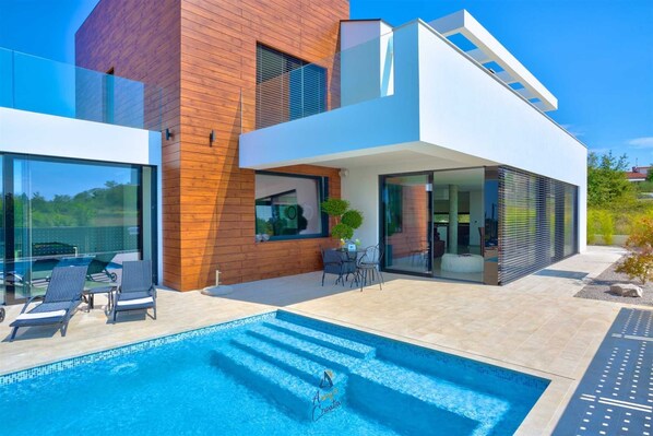A modern two-story house with a swimming pool, large windows, and a patio area. - Vibrant modern 5-BR Villa for 10+2, with pool and a sea view (Višnjan)