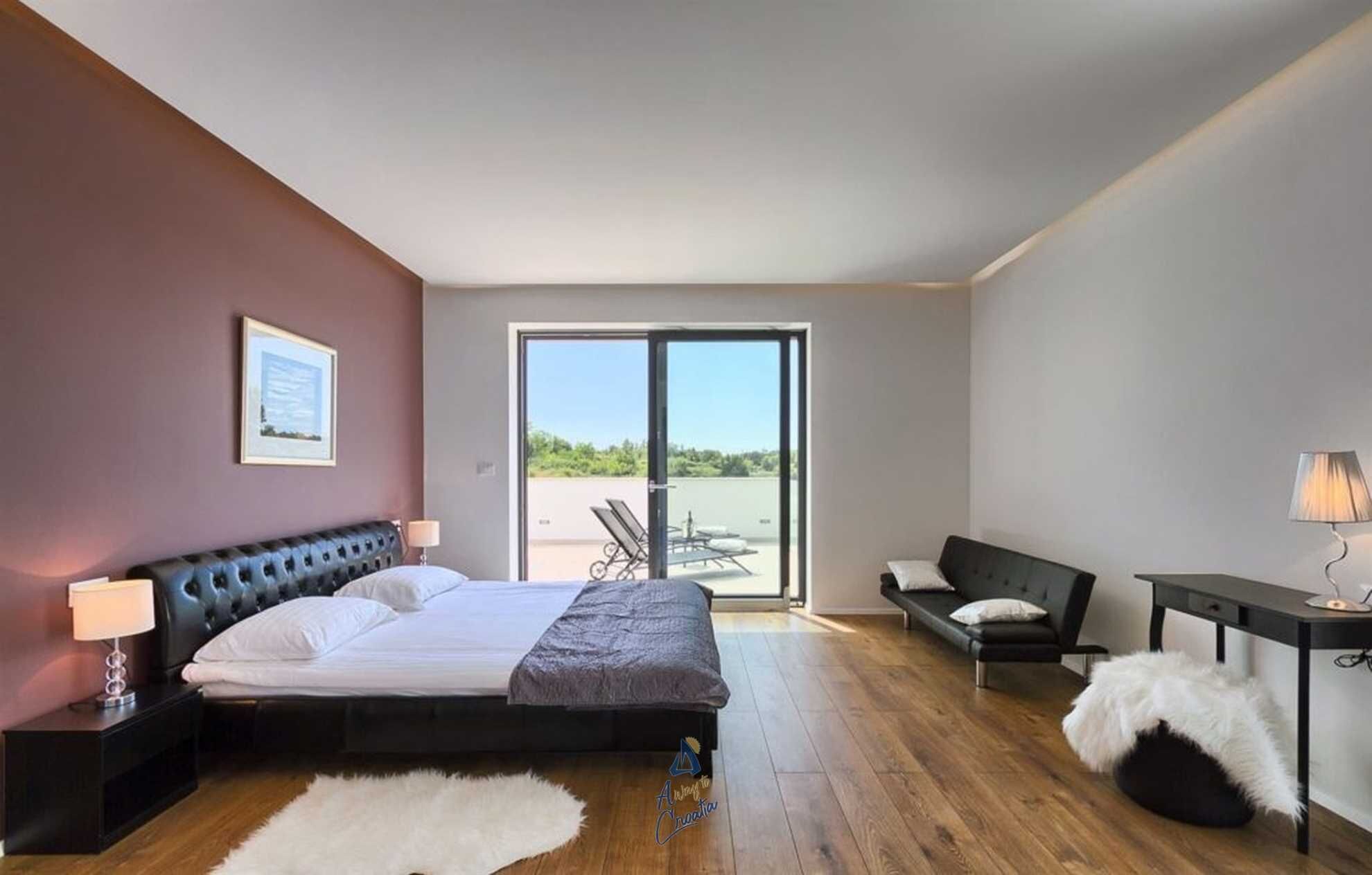 Quarto moderno com cama, escrivaninha, cadeira e sofá.